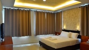 A modern hotel room with a large bed, a flat-screen TV, and a ceiling light fixture.