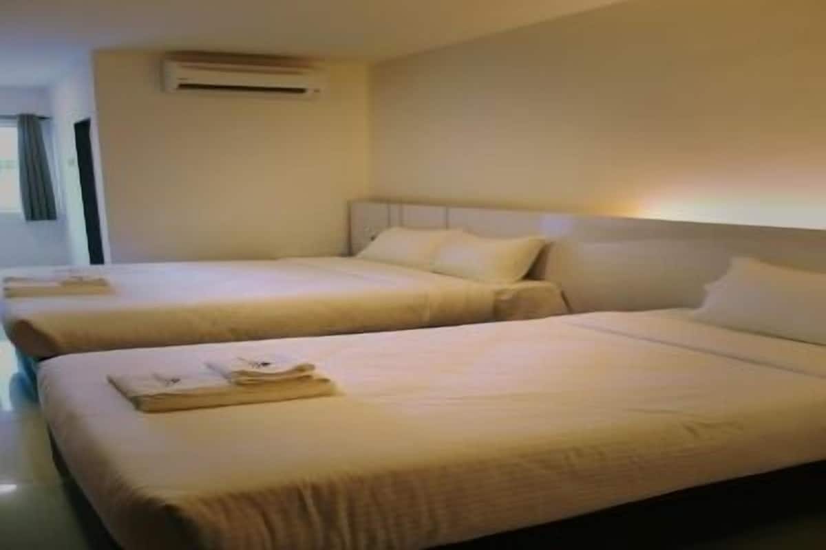 A hotel room with two beds, each with a neatly folded towel.