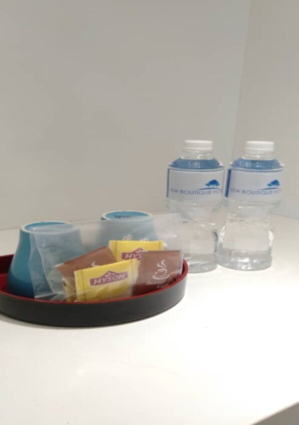 Bandeja con vasos desechables, una caja de pañuelos y una botella de agua sobre una superficie blanca.
