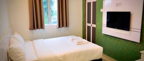 A hotel room with a bed, a TV mounted on the wall, and a window with curtains.