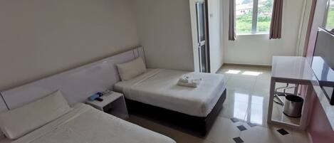 A hotel room with two beds, a TV, a mini-fridge, and a window with curtains.