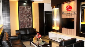 A modern hotel lobby with leather sofas, a glass coffee table, and a large flat-screen TV. - Hotel Harmony In Pontianak (Pontianak)