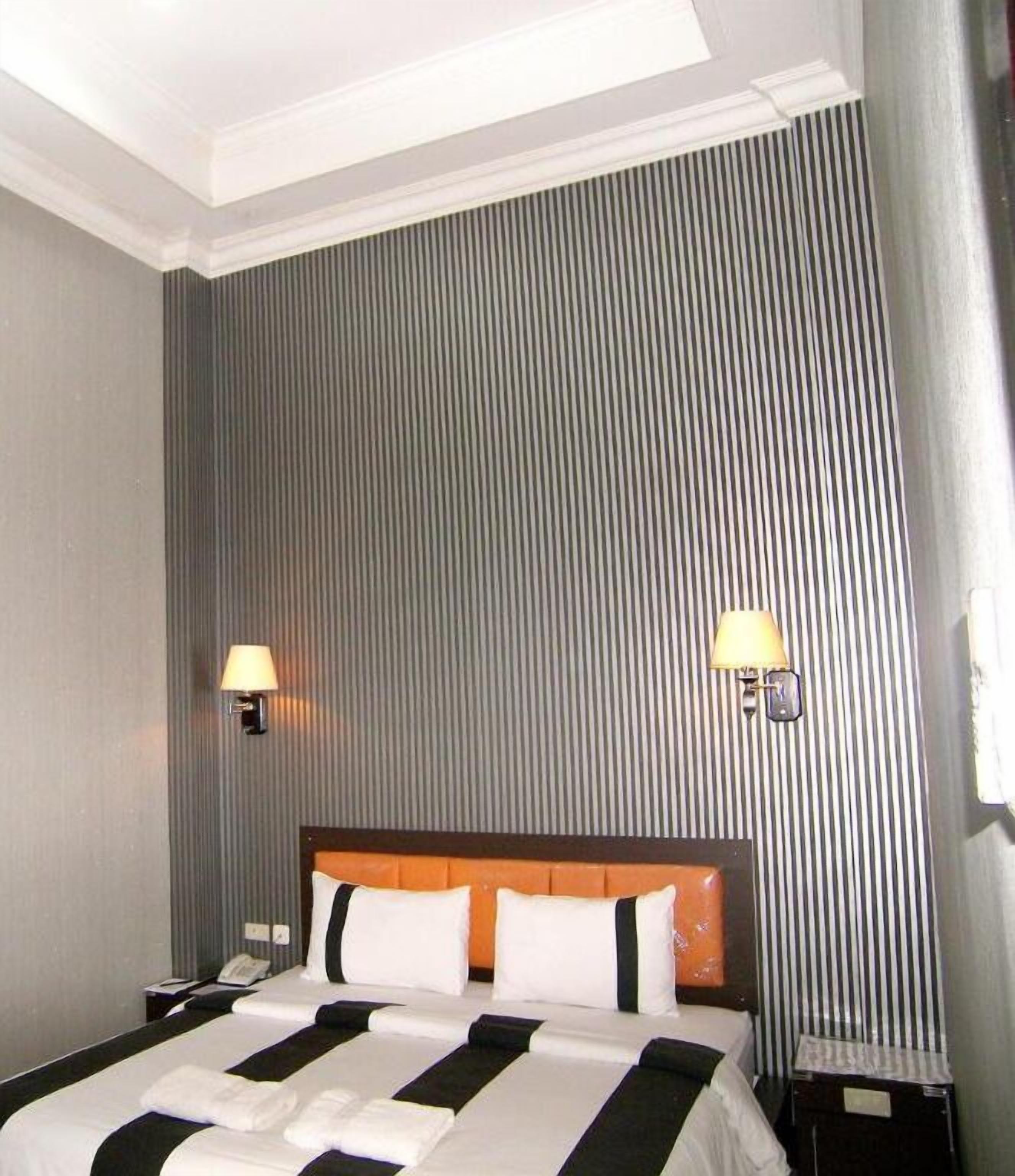Una habitación de hotel con una cama grande, dos lámparas de noche y un cabecero.