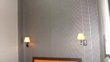 Una habitación de hotel con una cama grande, dos lámparas de noche y un cabecero.