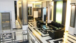 A modern lobby with a glass staircase, black and white patterned flooring, and leather seating areas. - Hotel Harmony In Pontianak (Pontianak)