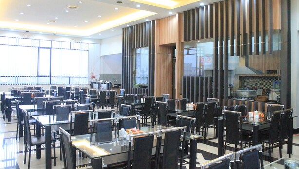 A spacious restaurant with multiple tables and chairs, a modern ceiling design, and large windows allowing natural light. - Hotel Harmony In Pontianak (Pontianak)