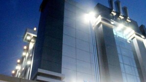 A modern building with a prominent vertical structure and multiple illuminated windows. - Hotel Harmony In Pontianak (Pontianak)