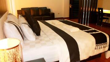 A hotel room with a large bed, a sofa, a desk, and a lamp.