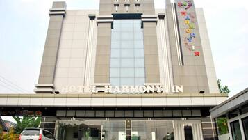 A modern hotel with a prominent sign reading "HOTEL HARMONY IN".
