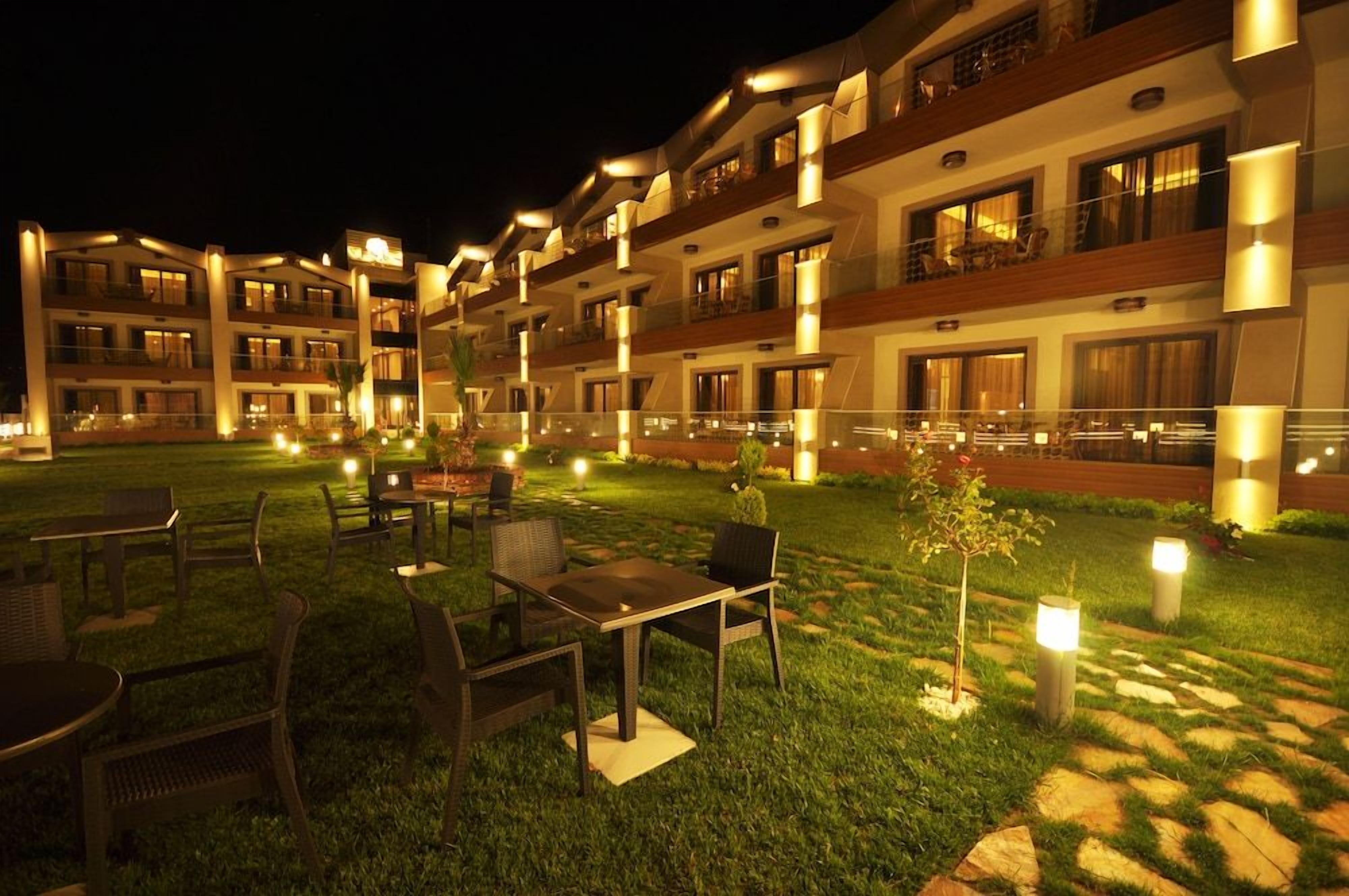 Een hotel binnenplaats 's nachts, met terrasmeubels en verlichte paden.