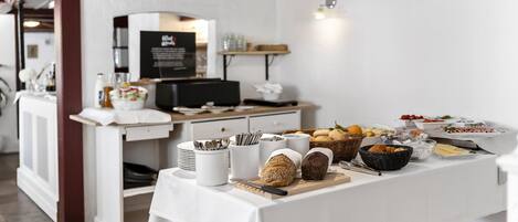 Una mesa de buffet con diferentes alimentos, una estación de café y un mostrador con una computadora.