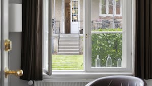Una habitación con vistas a un jardín, una puerta y una ventana con cortinas.