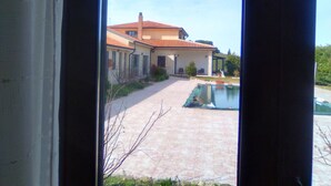 Una casa con patio de baldosas y piscina.