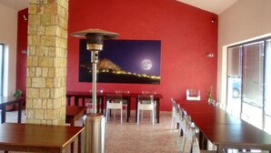 Un restaurante con un pilar de piedra, un cuadro grande de un paisaje iluminado por la luna y una larga mesa de comedor con sillas.