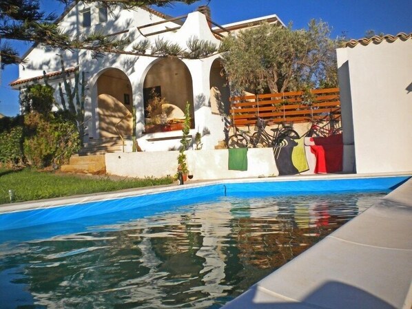 Una piscina al aire libre de temporada, sombrillas, tumbonas