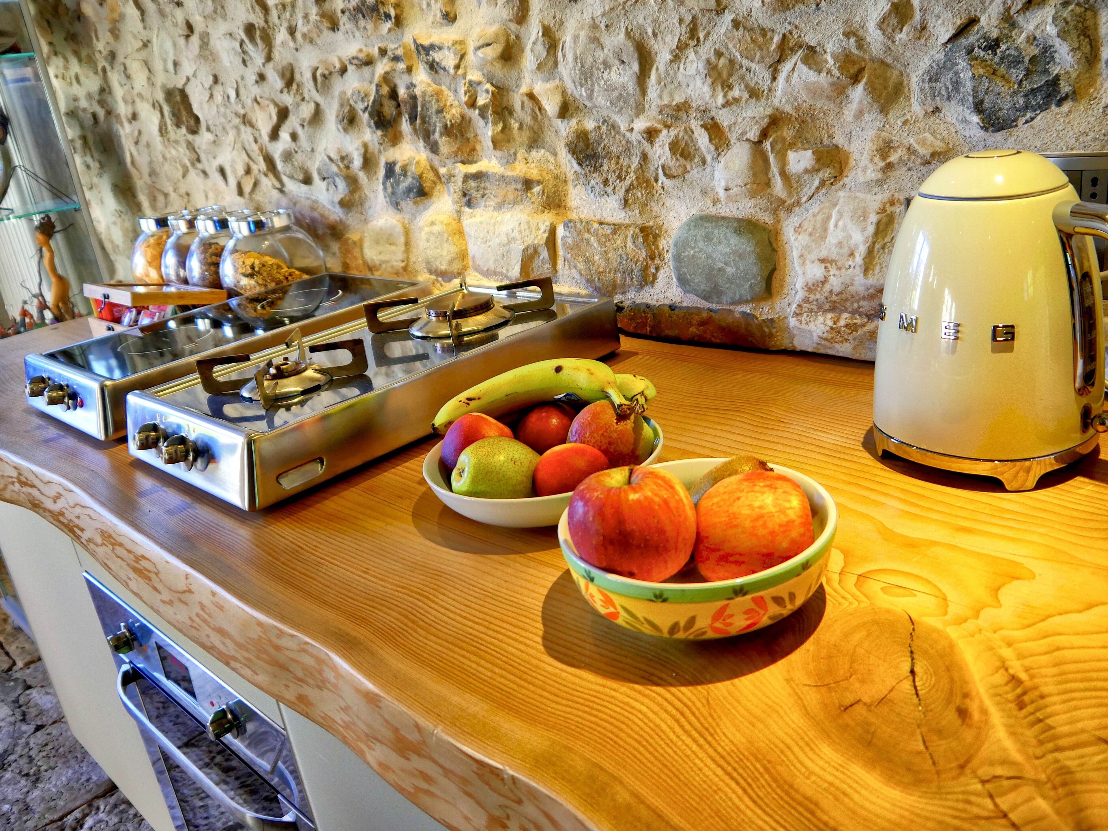 Una cocina con estufa a gas, un tostador y un cuenco de fruta en la encimera.