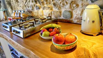 Una cocina con estufa a gas, un tostador y un cuenco de fruta en la encimera.
