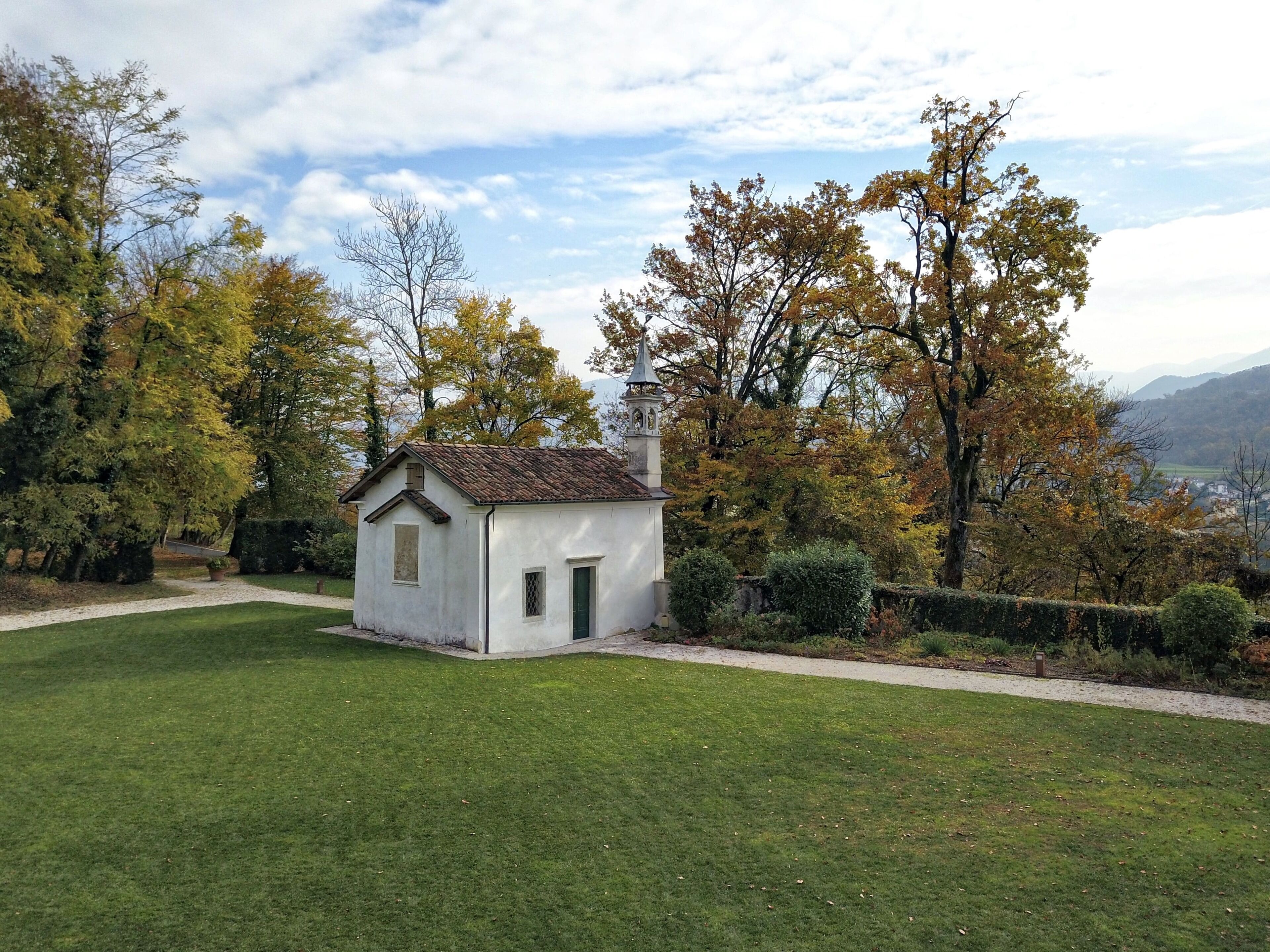 Un petit bâtiment blanc, doté d’un toit en tuiles, entouré d’une pelouse bien entretenue et d’arbres aux feuilles d’automne.