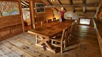 Un comedor de madera con una mesa grande y sillas, techo de madera y una ventana pequeña.