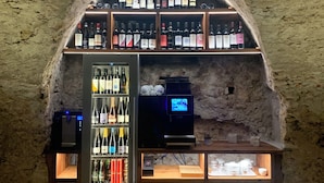 A bar with a stone arch ceiling, shelves of bottled beverages, a television, and a refrigerated display. - Villa San Liberale - Suites & Wellness - Villa Veneta (Feltre)