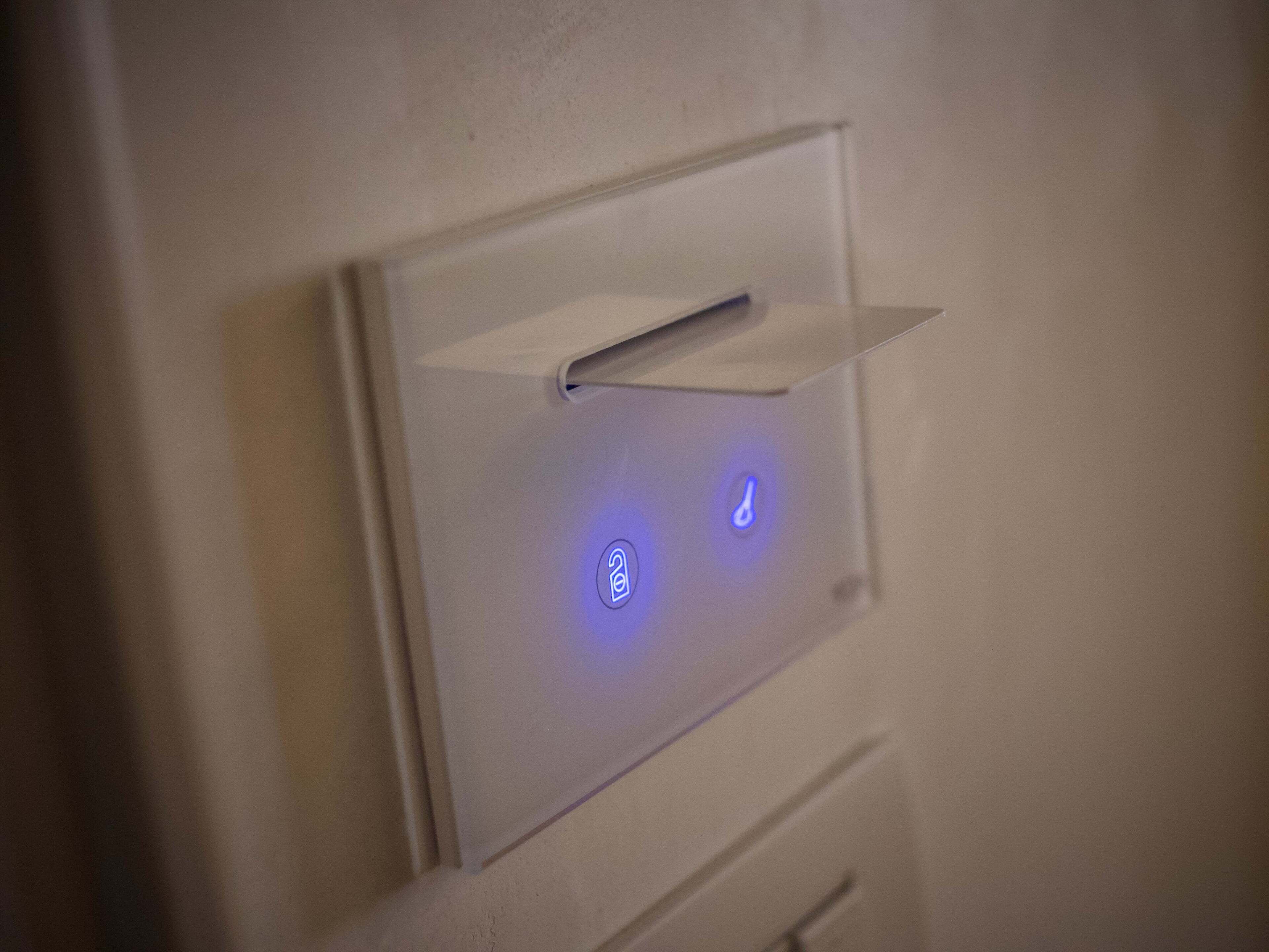 Un panel de control fijado a la pared, con botones iluminados y una ranura para tarjetas.