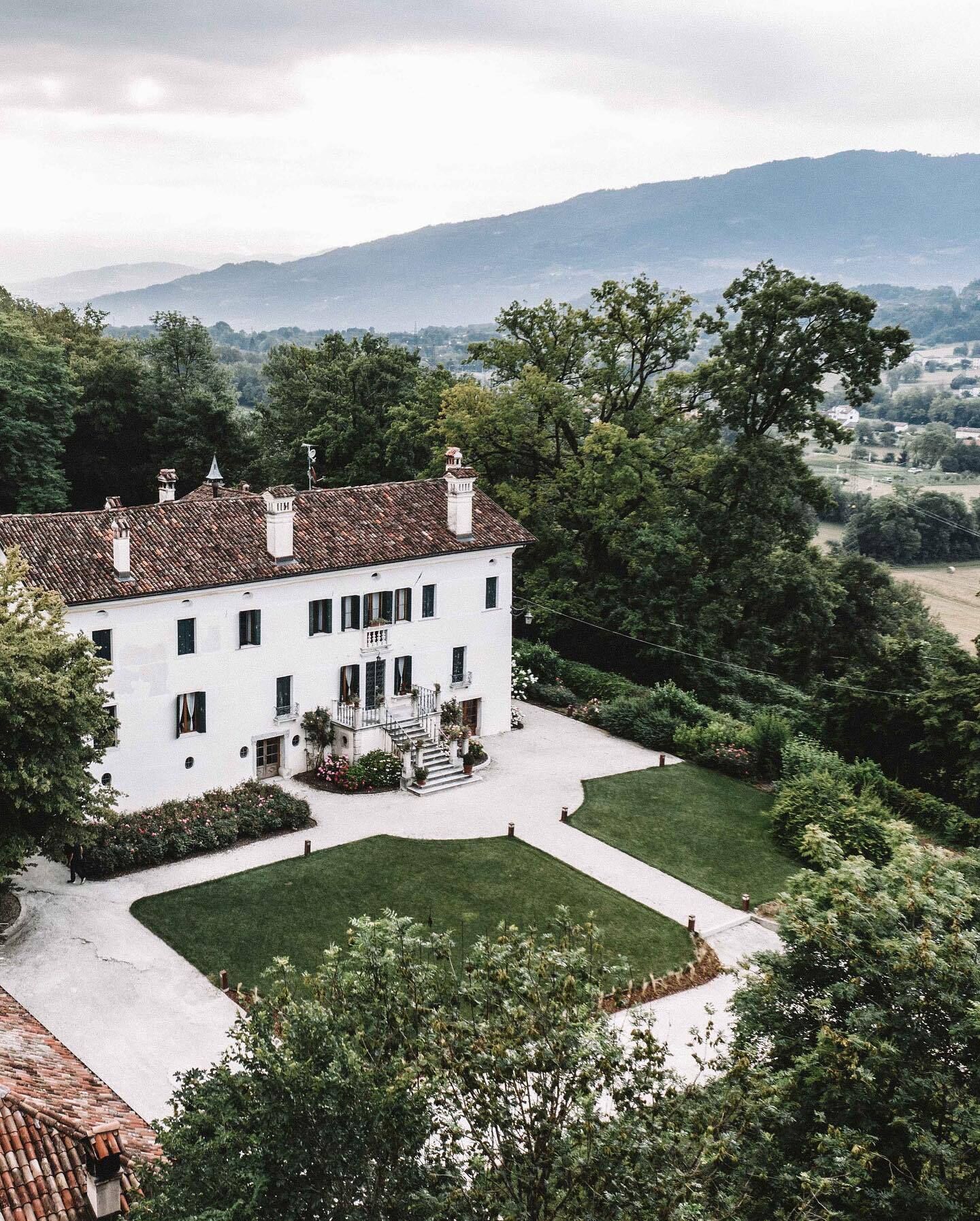 Un bâtiment blanc coiffé d’un toit en tuiles, entouré d’une végétation luxuriante et d’une pelouse bien entretenue.