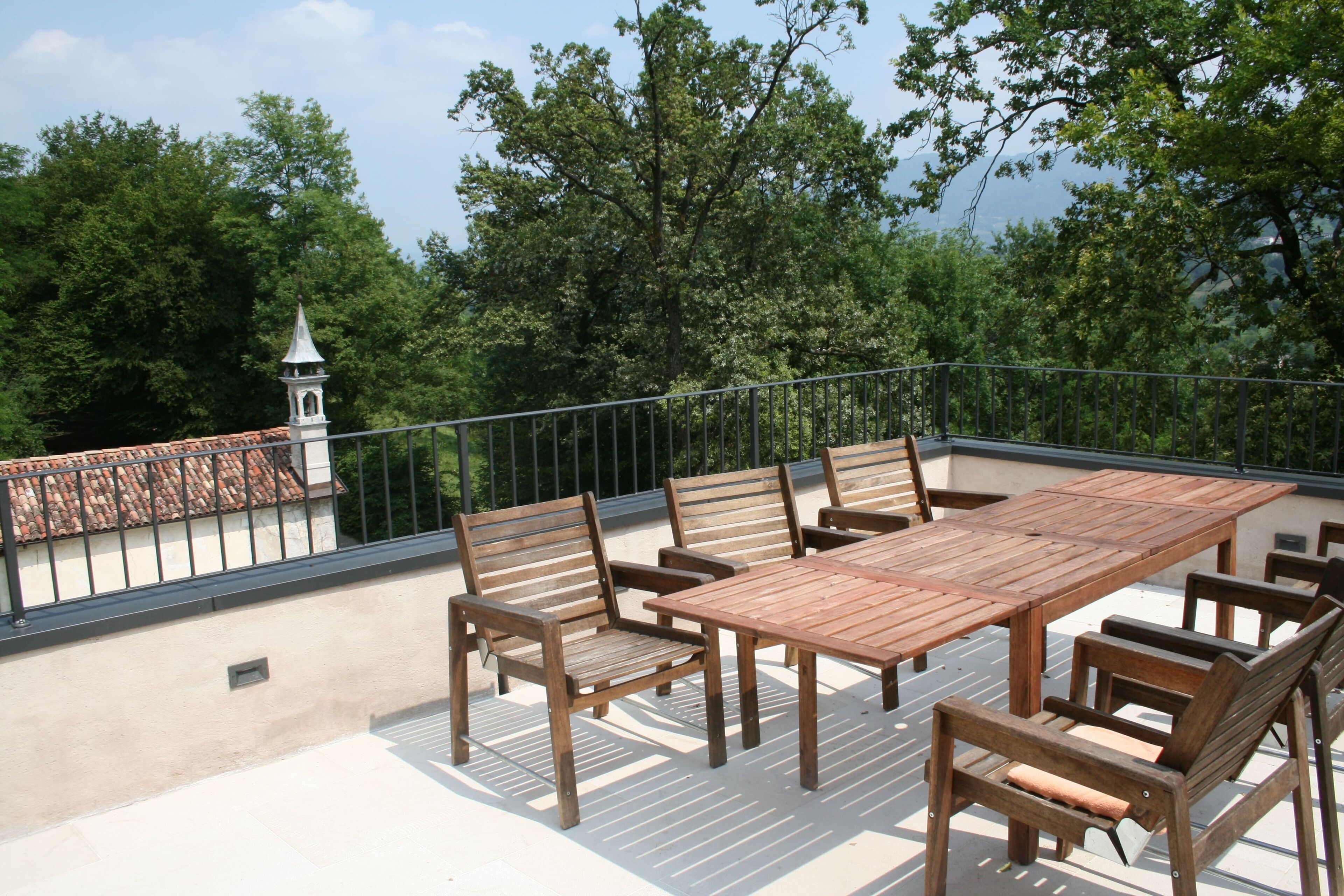 A wooden deck with a table and chairs, surrounded by a metal railing.