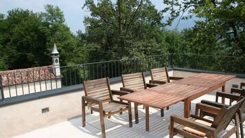 A wooden deck with a table and chairs, surrounded by a metal railing.
