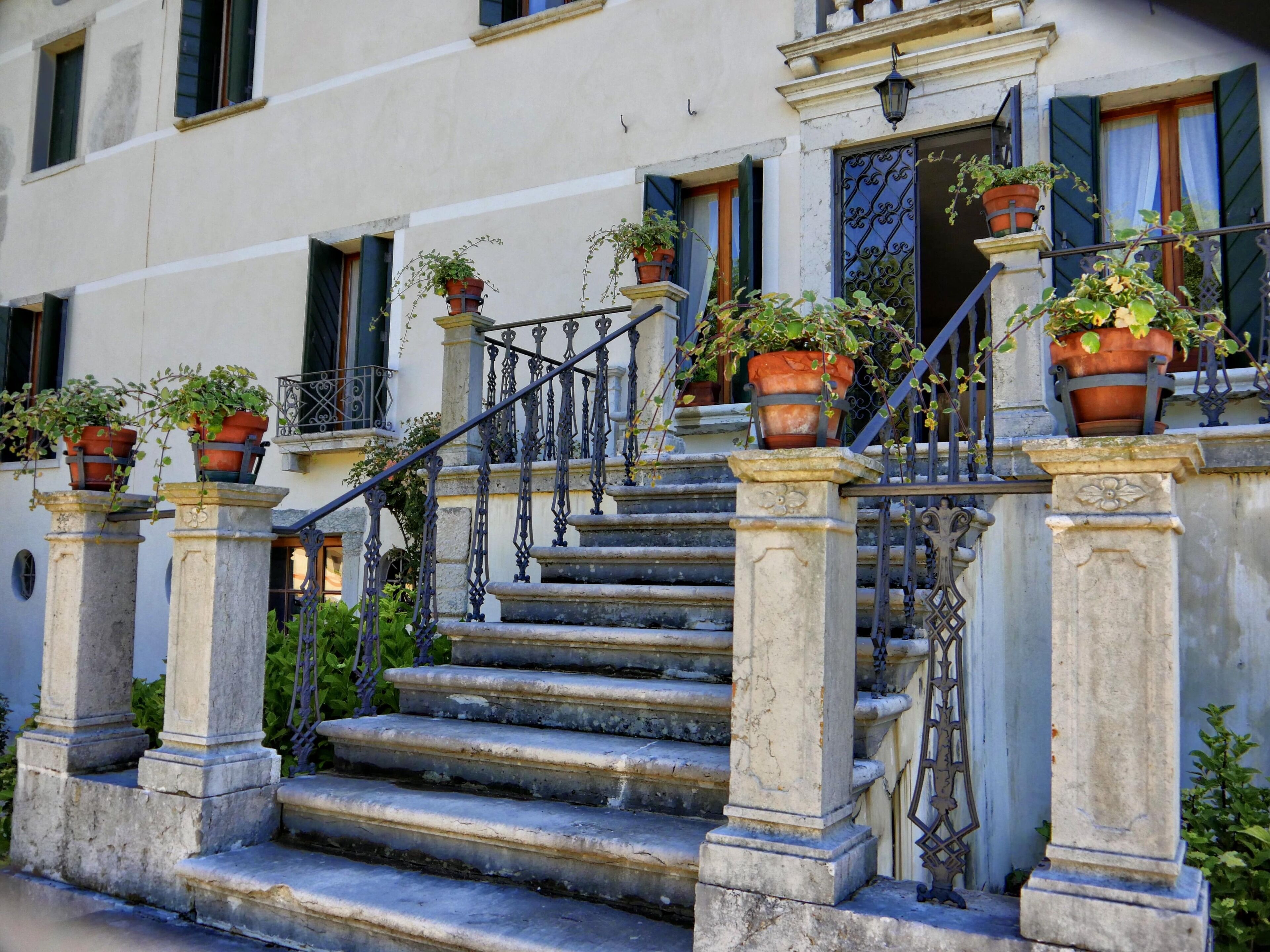 Un bâtiment doté d’un escalier menant à une porte surmontée d’un portail en fer forgé.