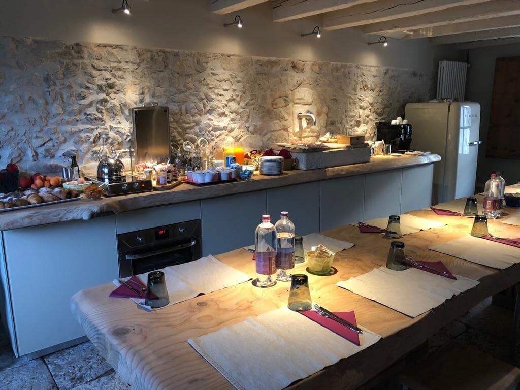 A kitchen with a stone wall, a wooden countertop, and various kitchen appliances and utensils.
