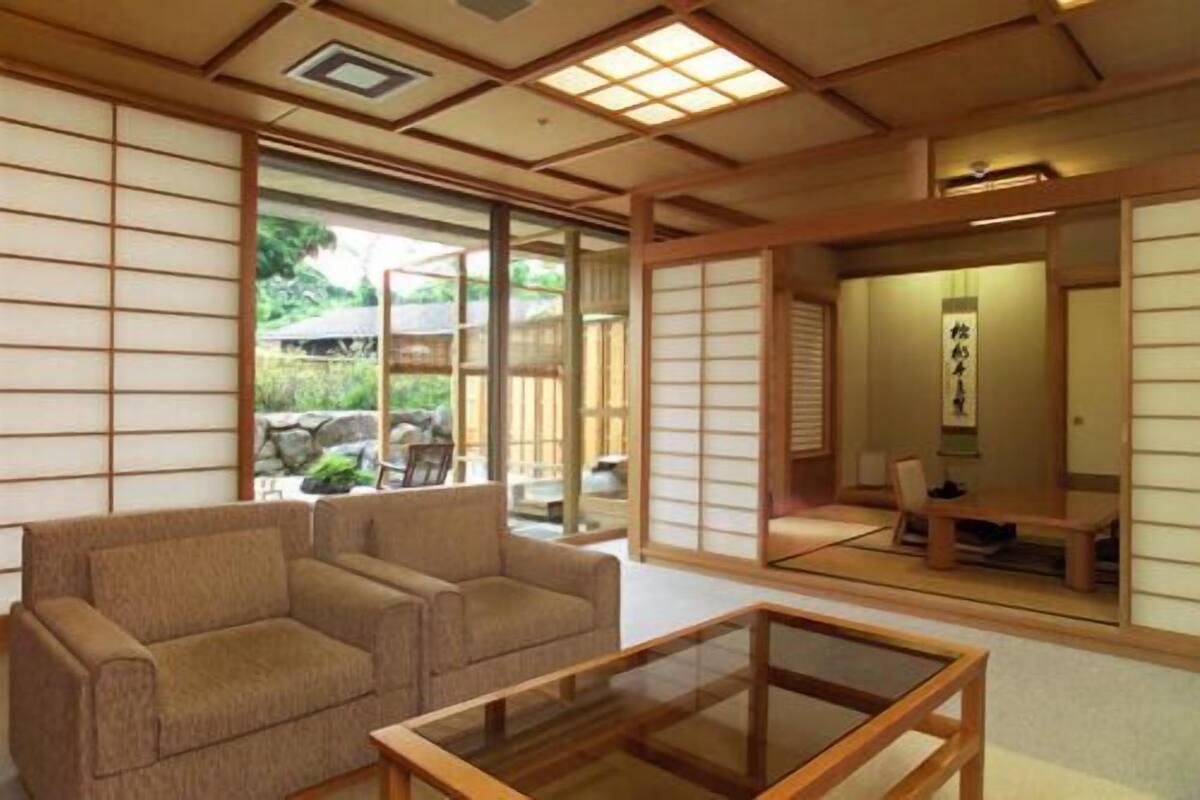 A traditional Japanese-style room with tatami mat flooring, a low wooden table, and a sofa.