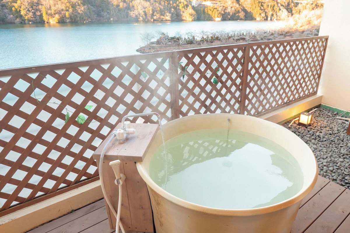 Ein Whirlpool auf einer Holzterrasse mit Blick auf einen See und einem Holzzaun.