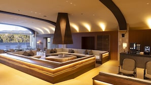 A modern lounge area with a large seating arrangement, a coffee machine, and a view of the outdoors. - Ooedo Onsen Monogatari Premium Enakyo (Ena)
