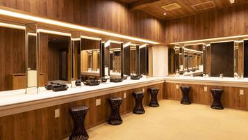 Een moderne badkamer met houten wanden, meerdere spiegels en zwarte krukken.