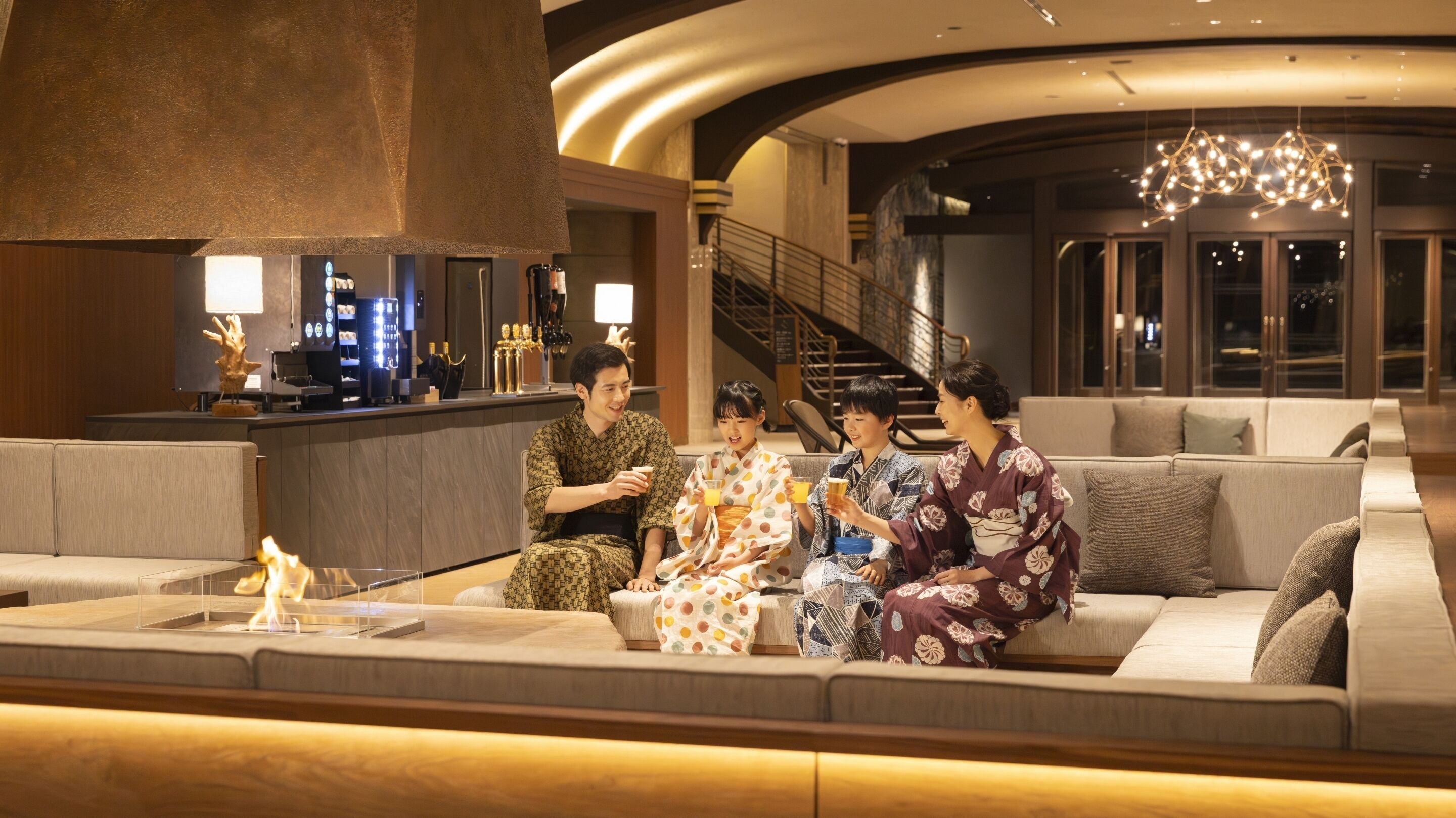 A modern lobby with a seating area, a staircase, and a bar.