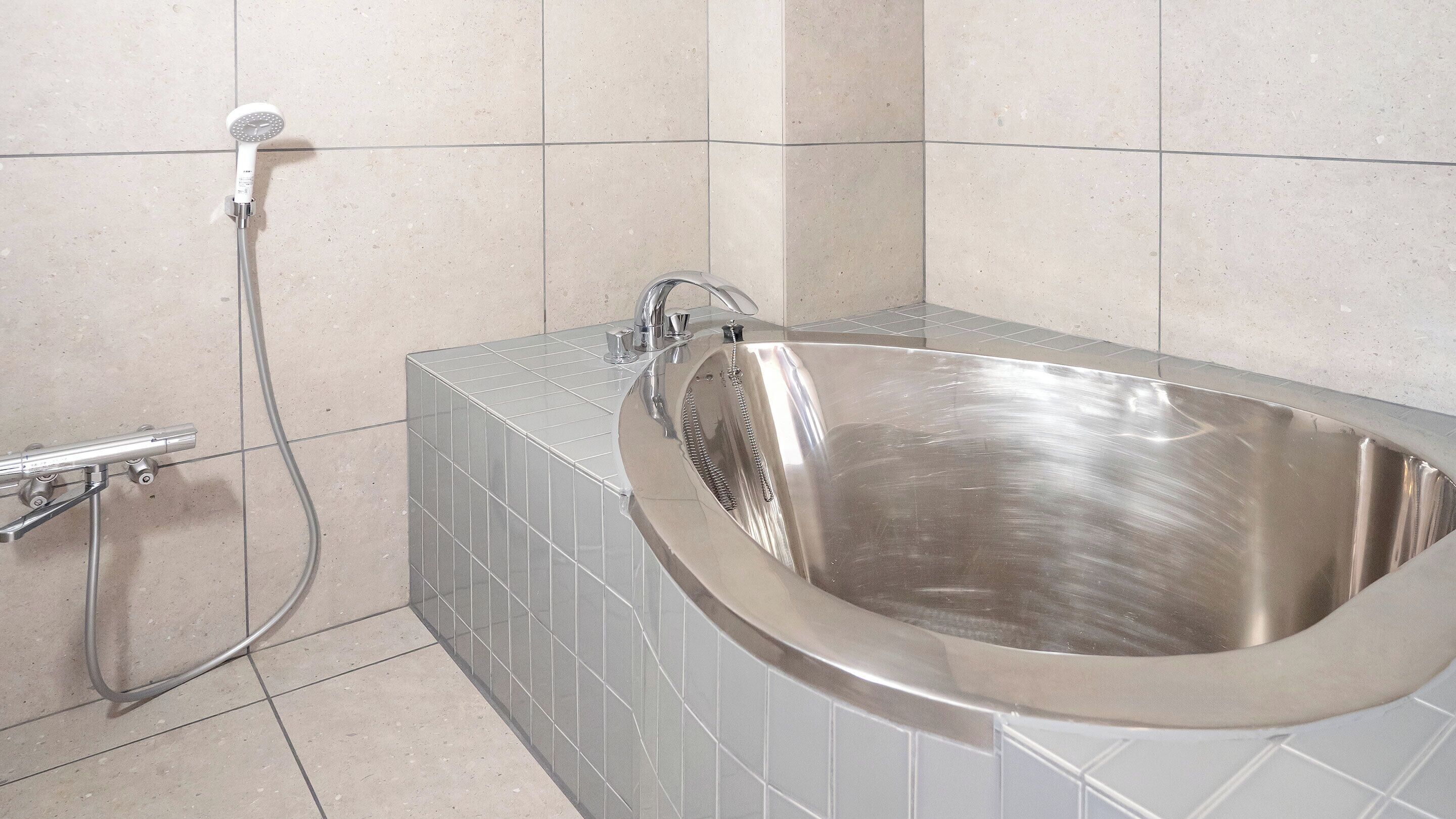 Ein modernes Badezimmer mit freistehender Badewanne, Duschbrausehandstück und Wandarmatur.