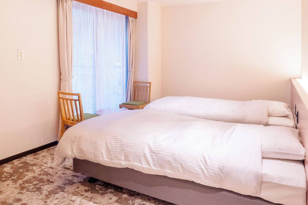 A bedroom with a bed, a chair, and a window with curtains.