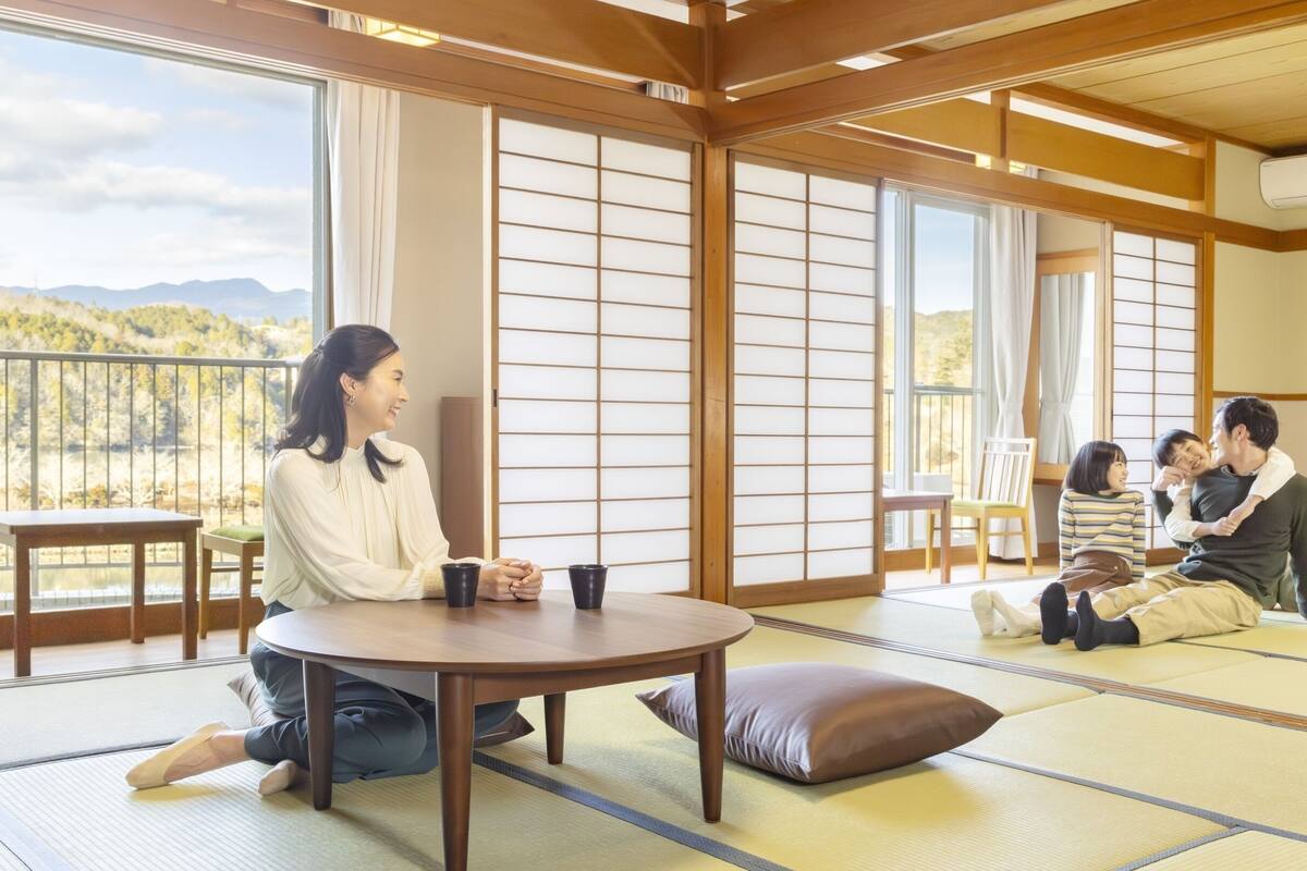 A tatami mat room with a low table, cushions, and sliding doors.