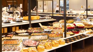 A buffet with various food items and a kitchen area in the background. - Ooedo Onsen Monogatari Premium Enakyo (Ena)