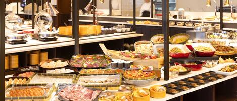 Un bufé con diversos alimentos y una cocina al fondo.