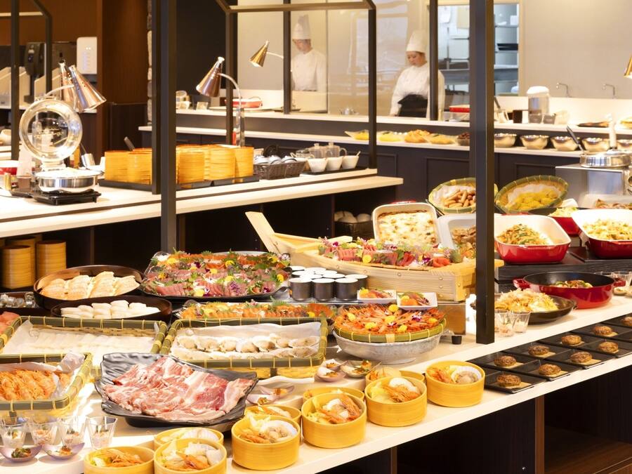 Un bufé con diversos alimentos y una cocina al fondo.