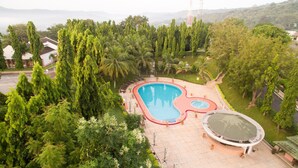 An aerial view of a resort with a large swimming pool, surrounded by lush greenery and palm trees. - Volta Hotel Akosombo (Akosombo)