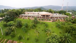 A large building with a flat roof, surrounded by well-maintained green lawns and palm trees. - Volta Hotel Akosombo (Akosombo)