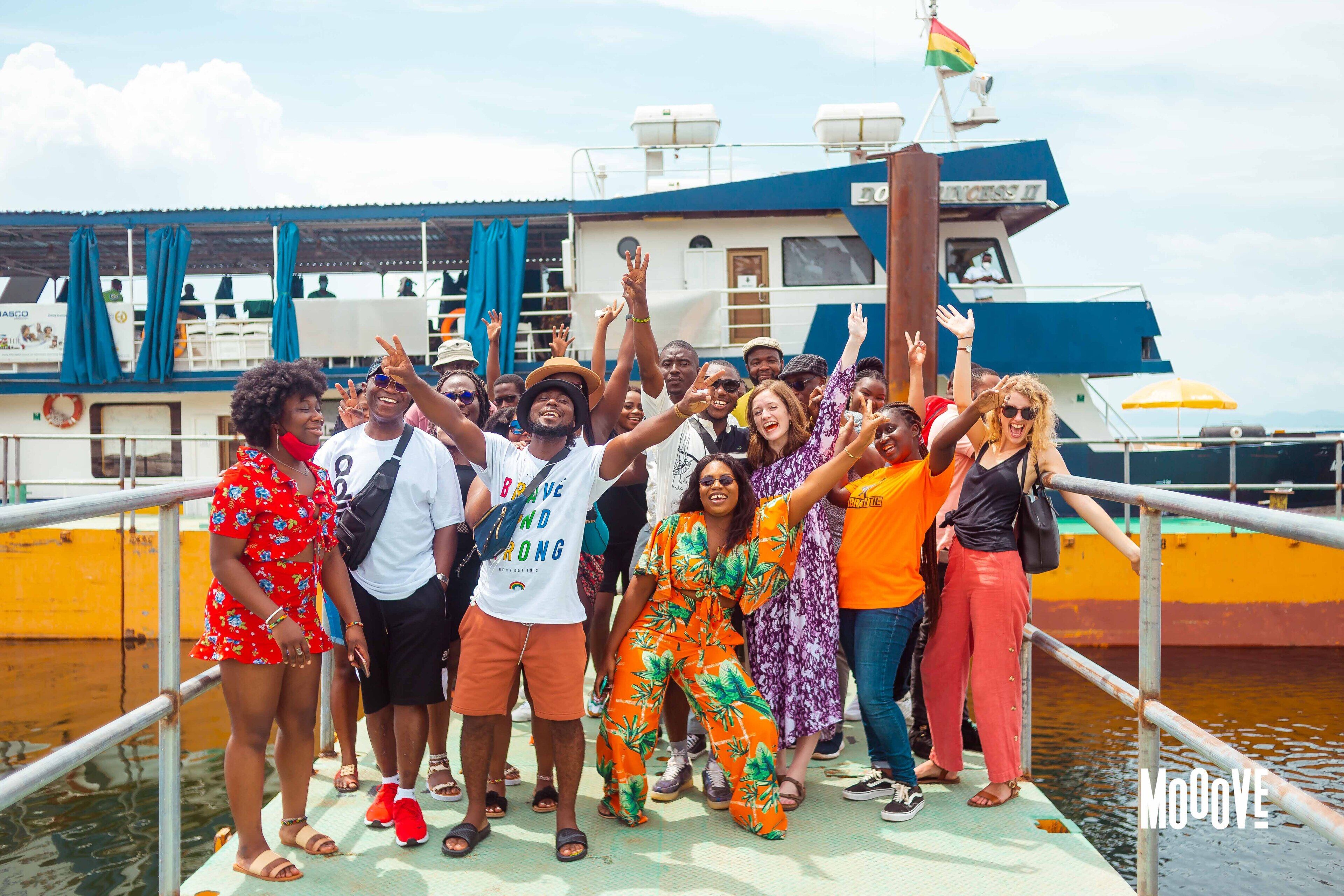 A group of people on a boat deck with a large vessel in the background.