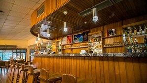 A bar area with wooden paneling, bar stools, and shelves stocked with bottles. - Volta Hotel Akosombo (Akosombo)