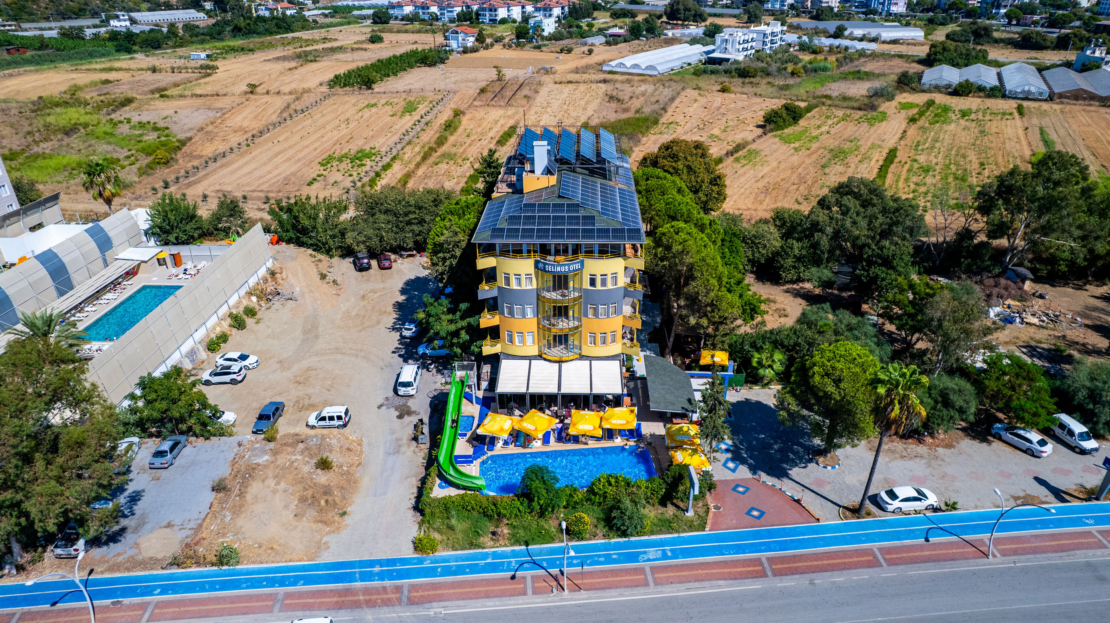 Vista aèria de l'Hotel Selinus amb una piscina, diverses plantes i panells solars.