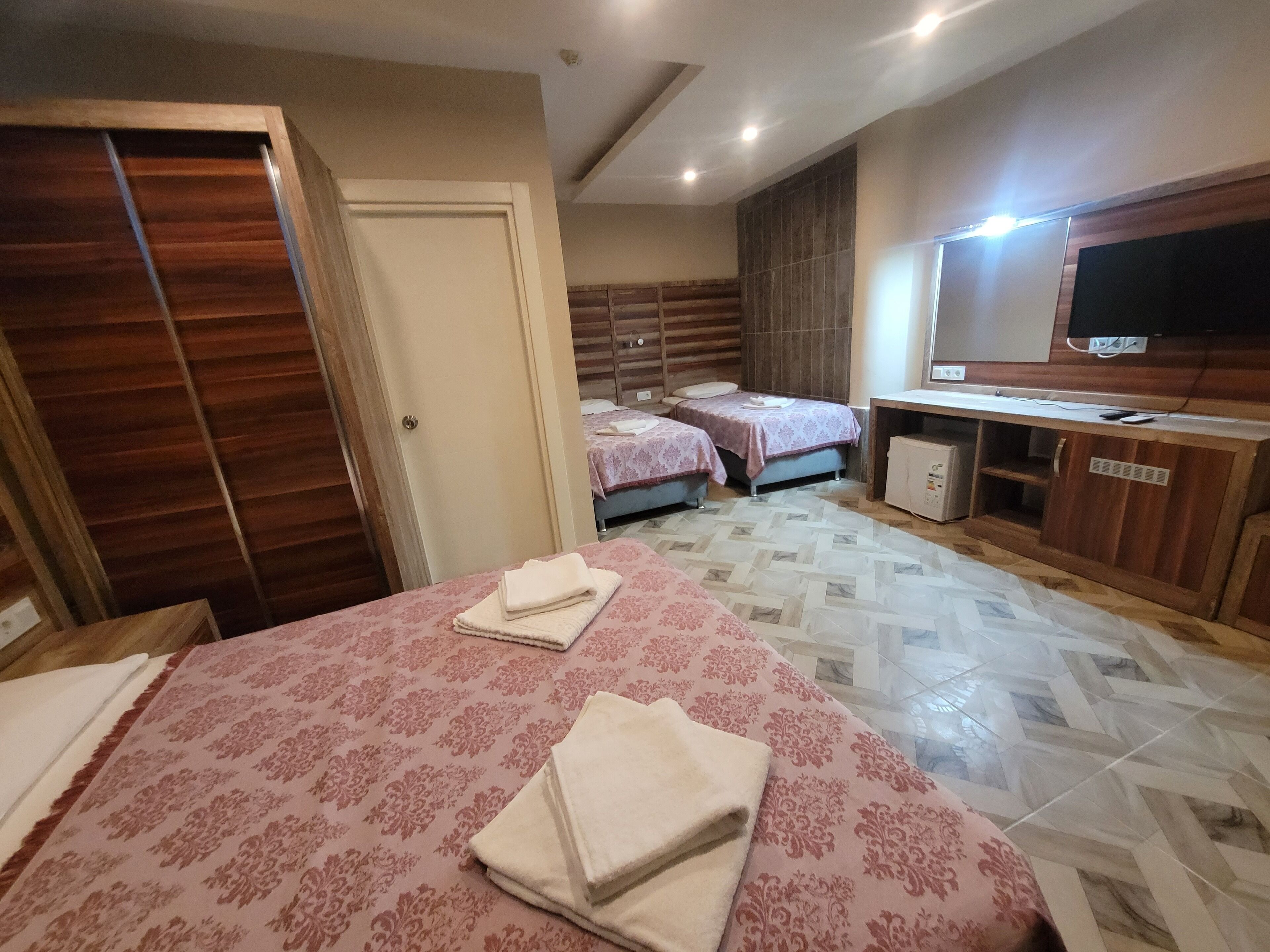 A hotel room with two beds, a TV, a desk, and a wardrobe.
