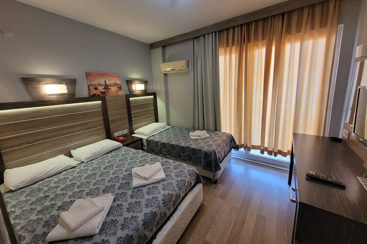 Een hotelkamer met twee bedden, een bureau en een televisie.