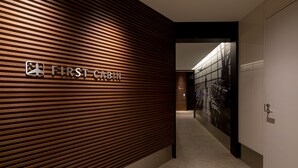 A hallway with a wooden slatted wall and a sign reading "FIRST CABIN". - First Cabin Akasaka (Tokyo)