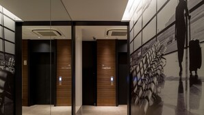 A modern airport terminal with a check-in area, seating, and a large mural of a person with luggage. - First Cabin Akasaka (Tokyo)